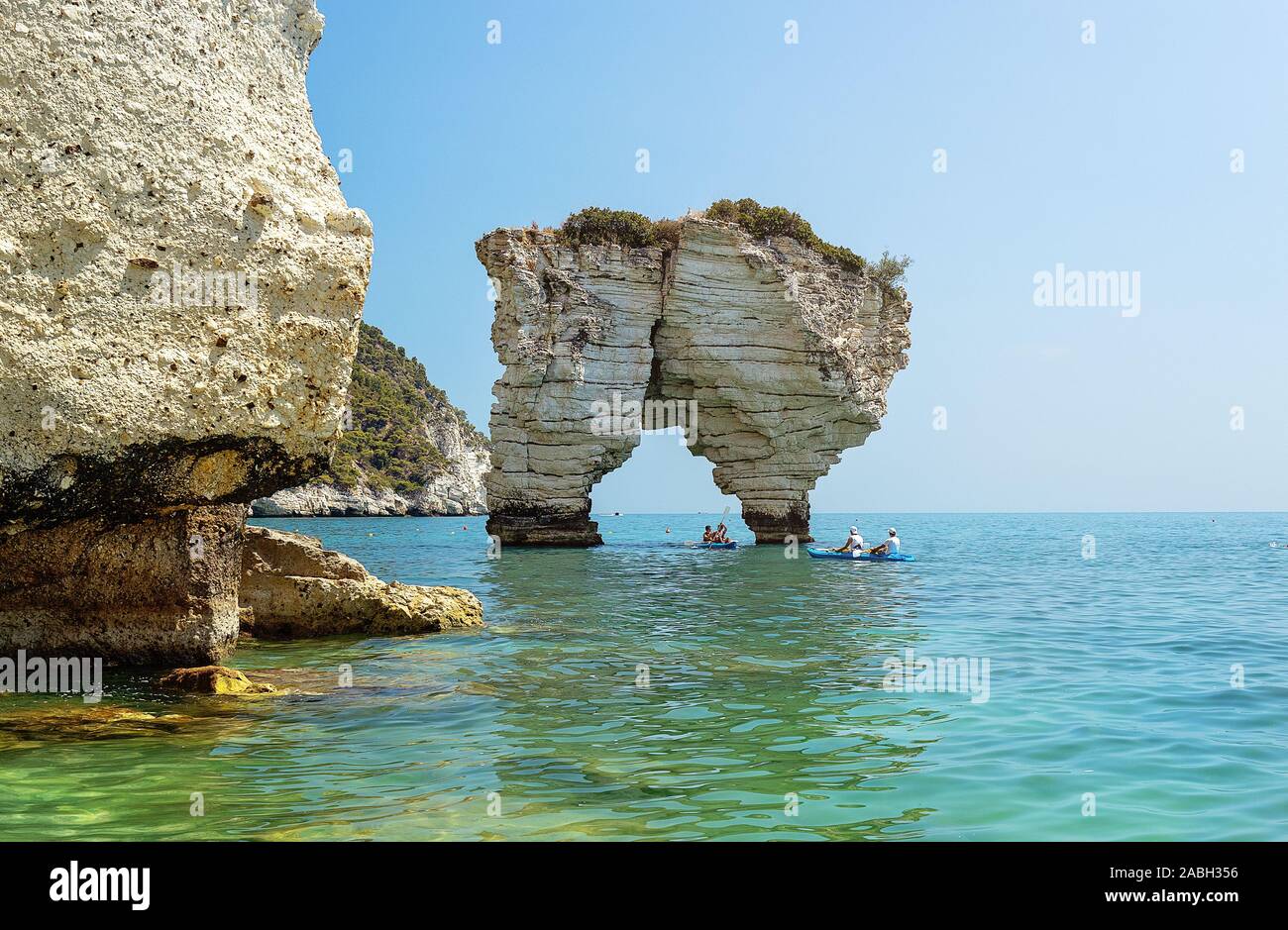 Les touristes non identifiables avec des kayaks à Faraglioni di Puglia Baia delle Zagare - célèbre plage en Italie Banque D'Images