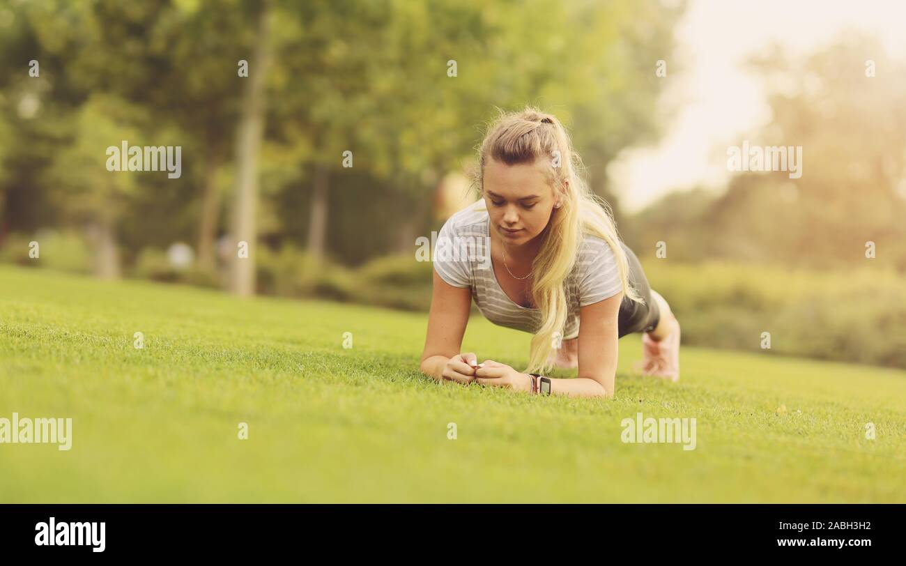 Fit woman faisant exercice de planches dans le parc extérieur sur l'herbe verte de la matinée - style de vie sain, l'endurance et la motivation concept - Copie savs Banque D'Images