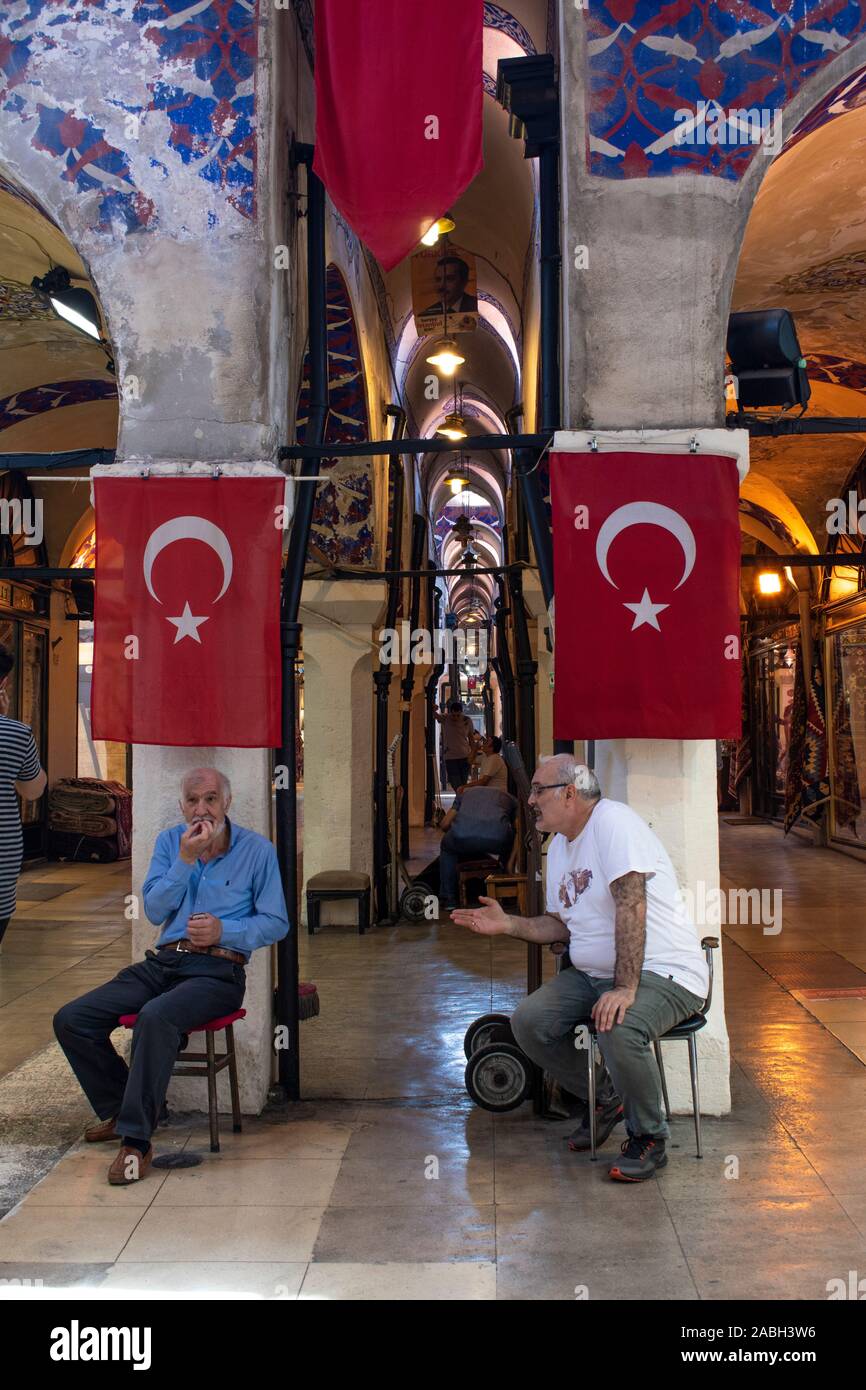 Istanbul : hommes turcs coin et de parler sous deux drapeaux turcs dans le Grand Bazar, un des plus grands et les plus anciens marchés couverts dans le monde Banque D'Images
