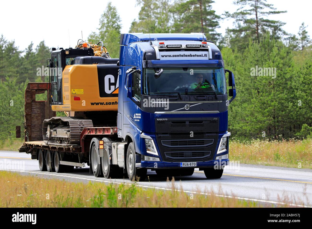 Volvo FH 500 bleu semi-remorque d'Santalan Betoni Oy parcours le long de l'excavateur à chenilles Cat finnois de l'autoroute 25, à l'été. Raasepori, Finlande. 12 juillet 2019 Banque D'Images