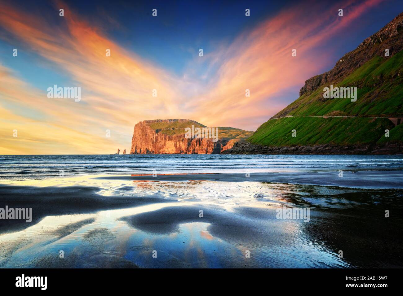 Coucher de soleil incroyable en temps de marée basse sur la côte de l'océan Atlantique près de village Tjornuvik. Célèbres formations rocheuses Risin et Kellingin Eidiskollur sur l'arrière-plan. Îles Féroé, Danemark. Photographie de paysage Banque D'Images