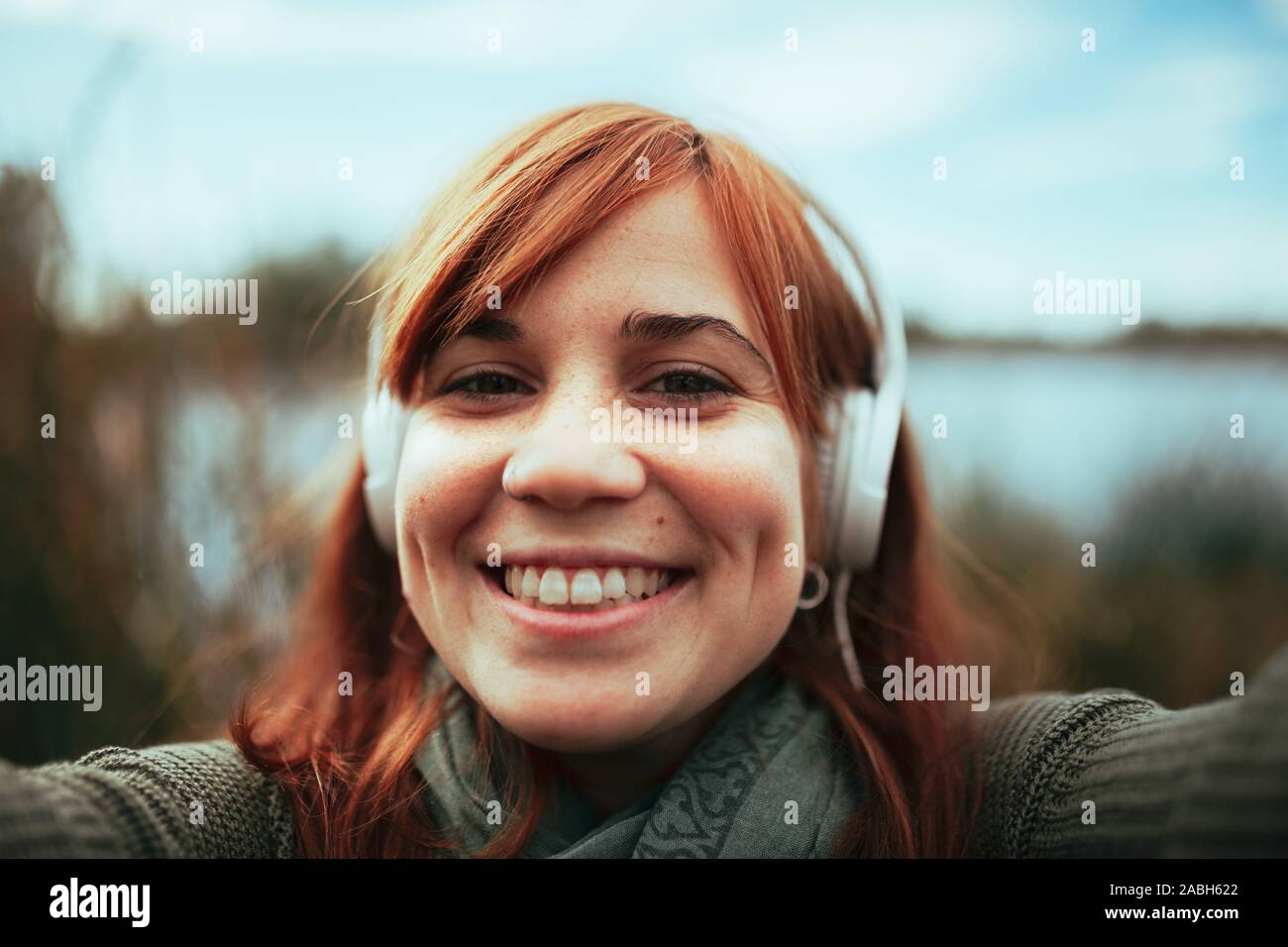 Jeune femme tenant un smartphone avec son selfies près d'un lac et d'écouteurs Banque D'Images
