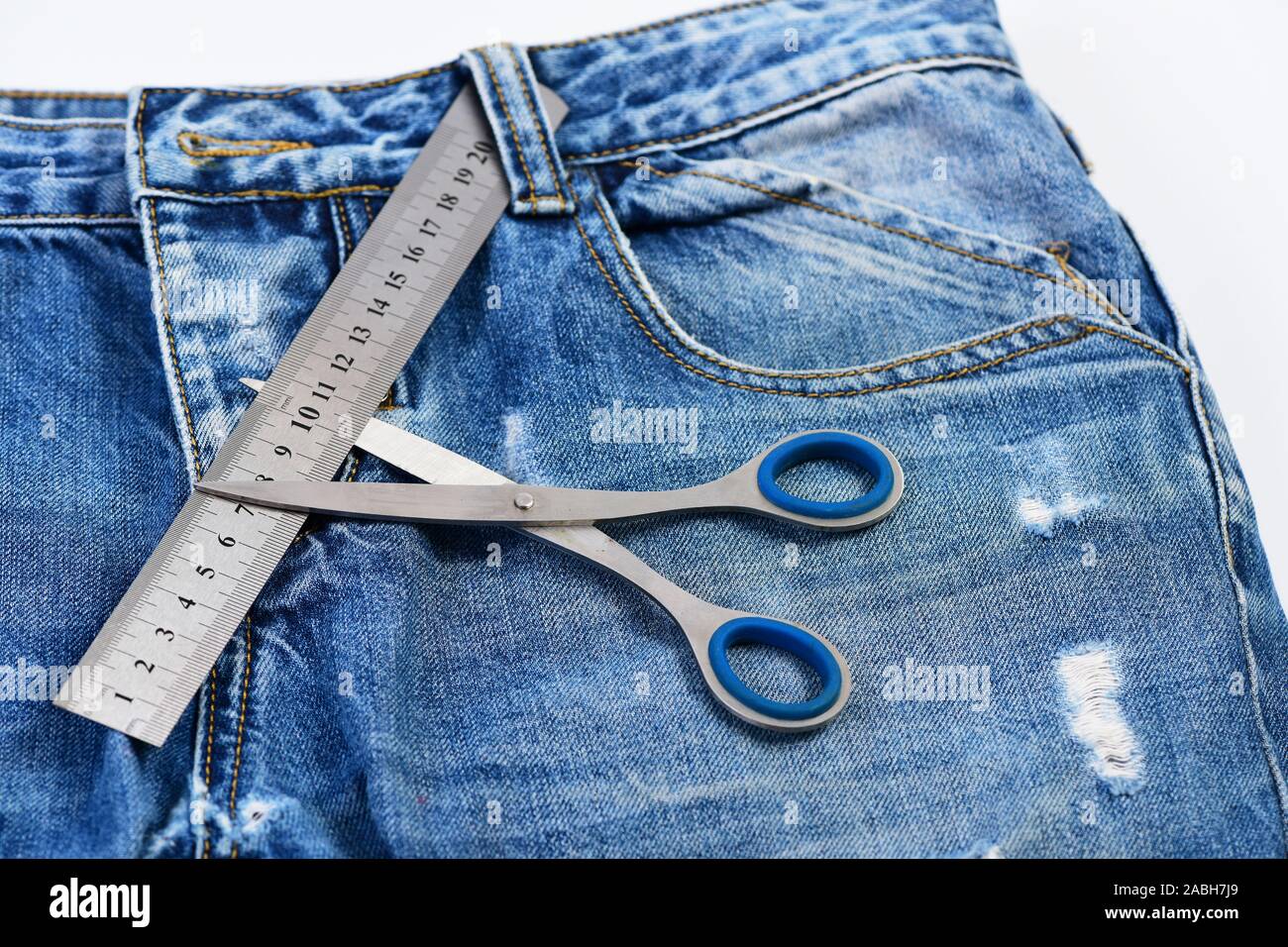 Outils de tailleurs sur tissu denim, selective focus. Entrejambe Jeans,  poche et passants, Close up. La fabrication de vêtements et de design  concept. Ciseaux de métal et d'une règle sur un jean