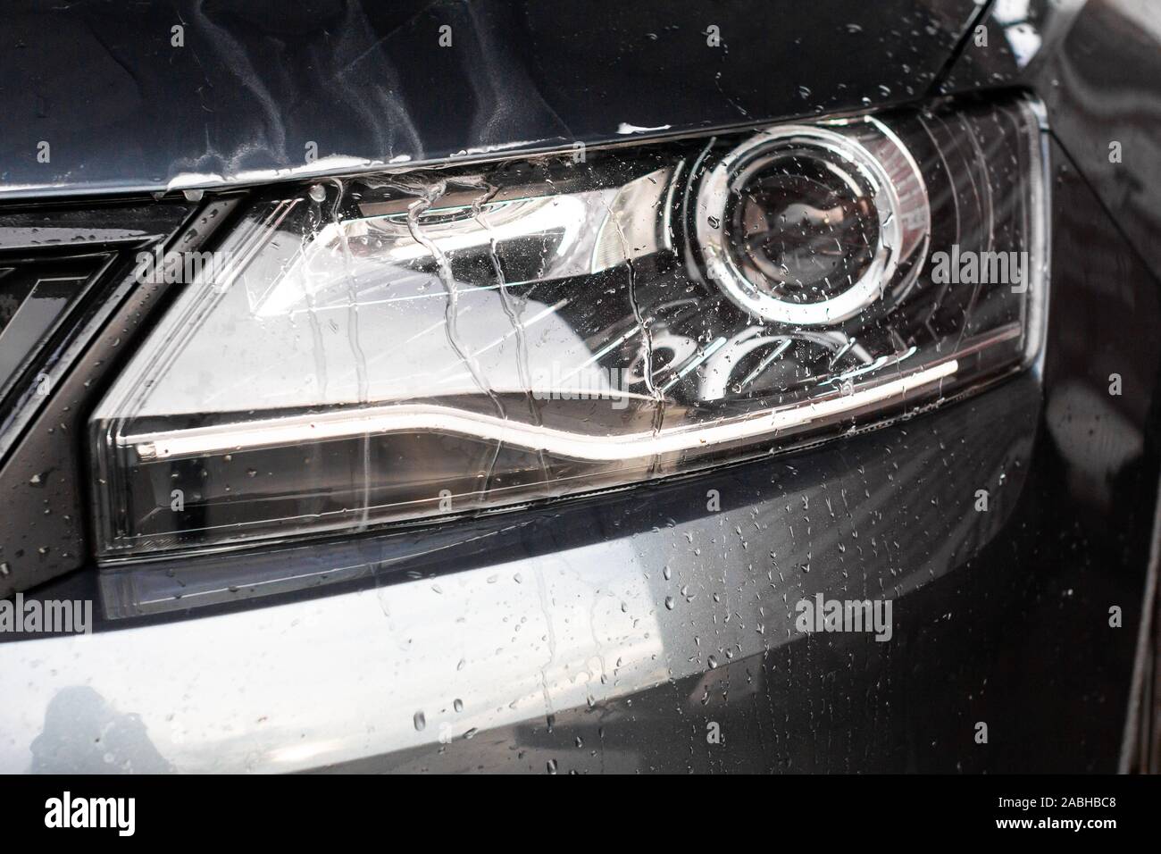 Gouttes d'eau et de la mousse sur la voiture lumière dans la station de lavage vehcle. Concept automobile de nettoyage, la pollution de l'eau souterraine. Banque D'Images