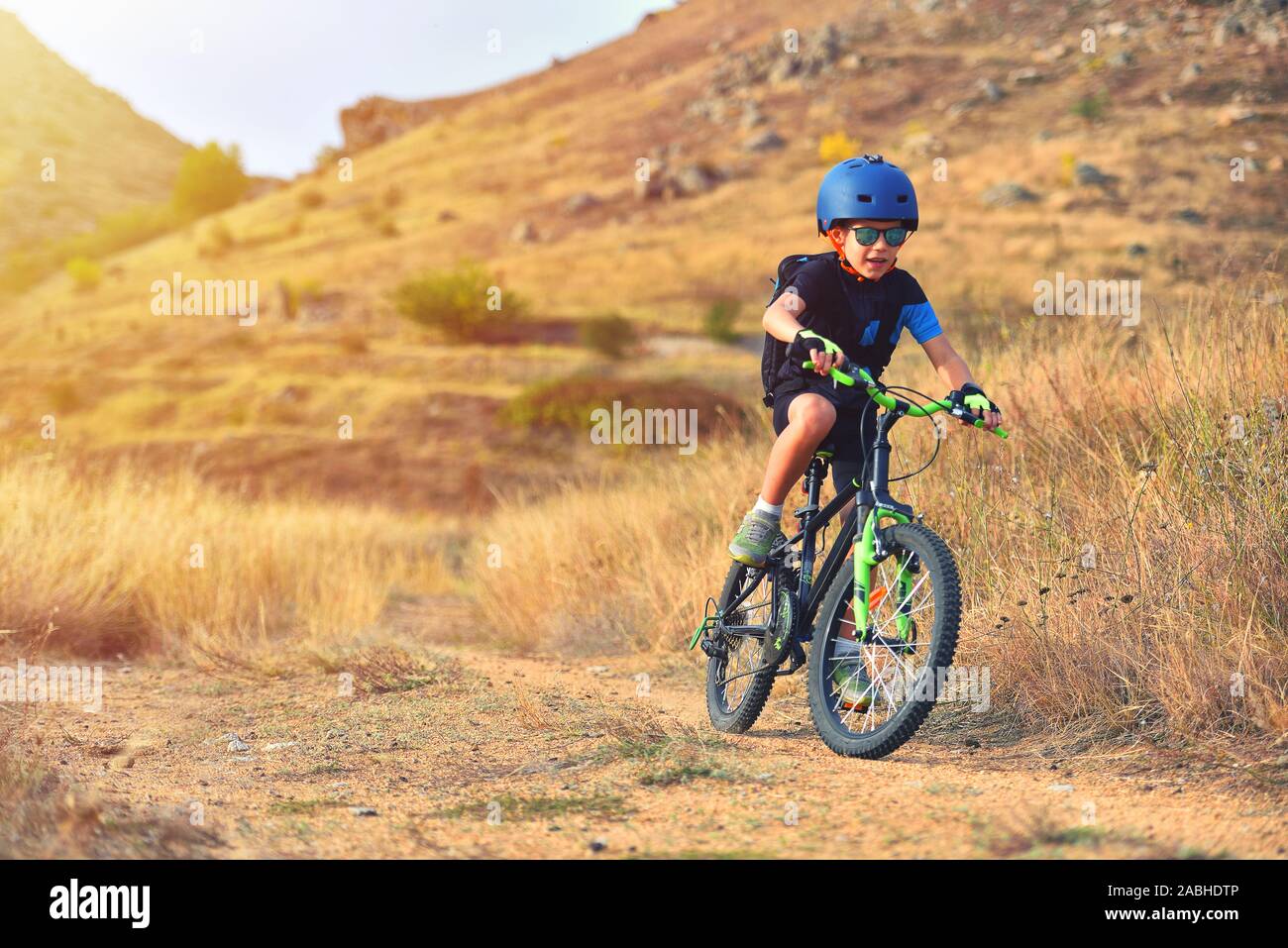 Happy kid garçon de 7 ans s'amuser dans le parc de l'automne avec un vélo sur belle journée d'automne. Casque de vélo enfant portant Active Banque D'Images