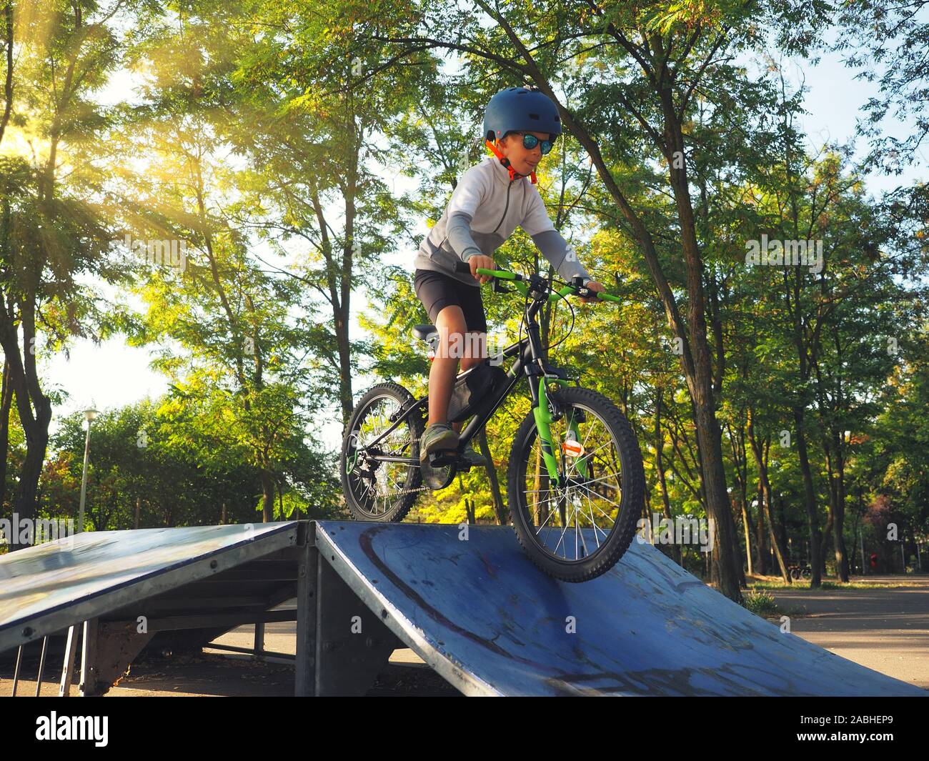 Happy kid garçon de 5 ans ayant in spring park avec un vélo sur belle journée d'automne. Casque de vélo enfant portant Active Banque D'Images