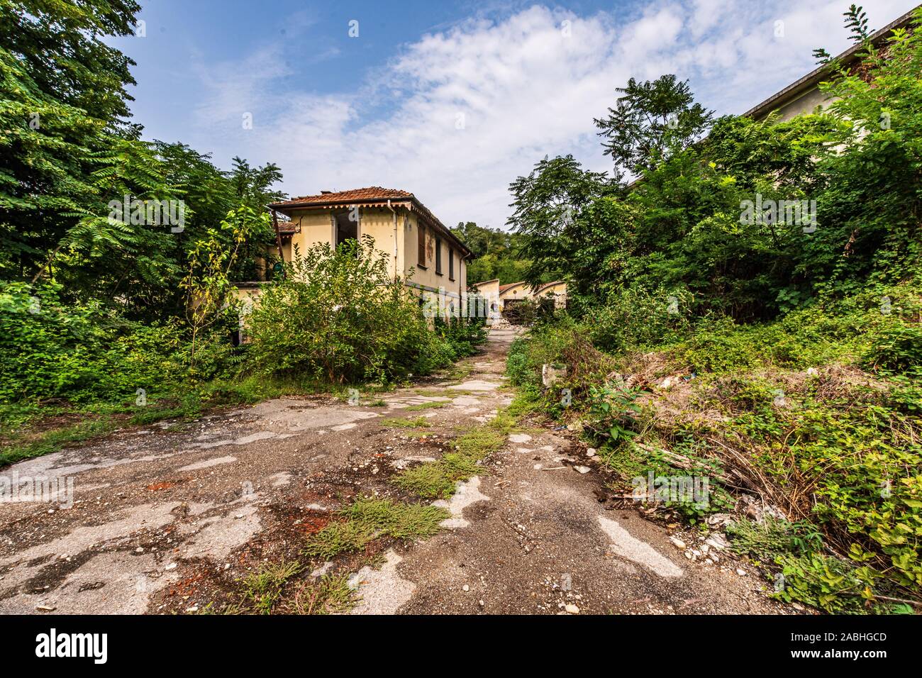 Route cahoteuse qui mène à un grand complexe industriel abandonné, un paysage de l'exploration urbaine aussi connu comme urbex Banque D'Images