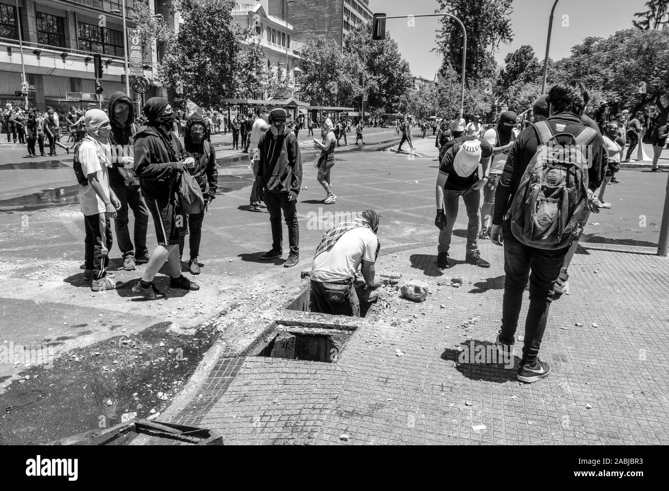 Des manifestants brisent des pierres à jeter à la police. Affrontements entre la police et de jeunes manifestants dans la rue Alameda lors des dernières émeutes à Santiago Banque D'Images