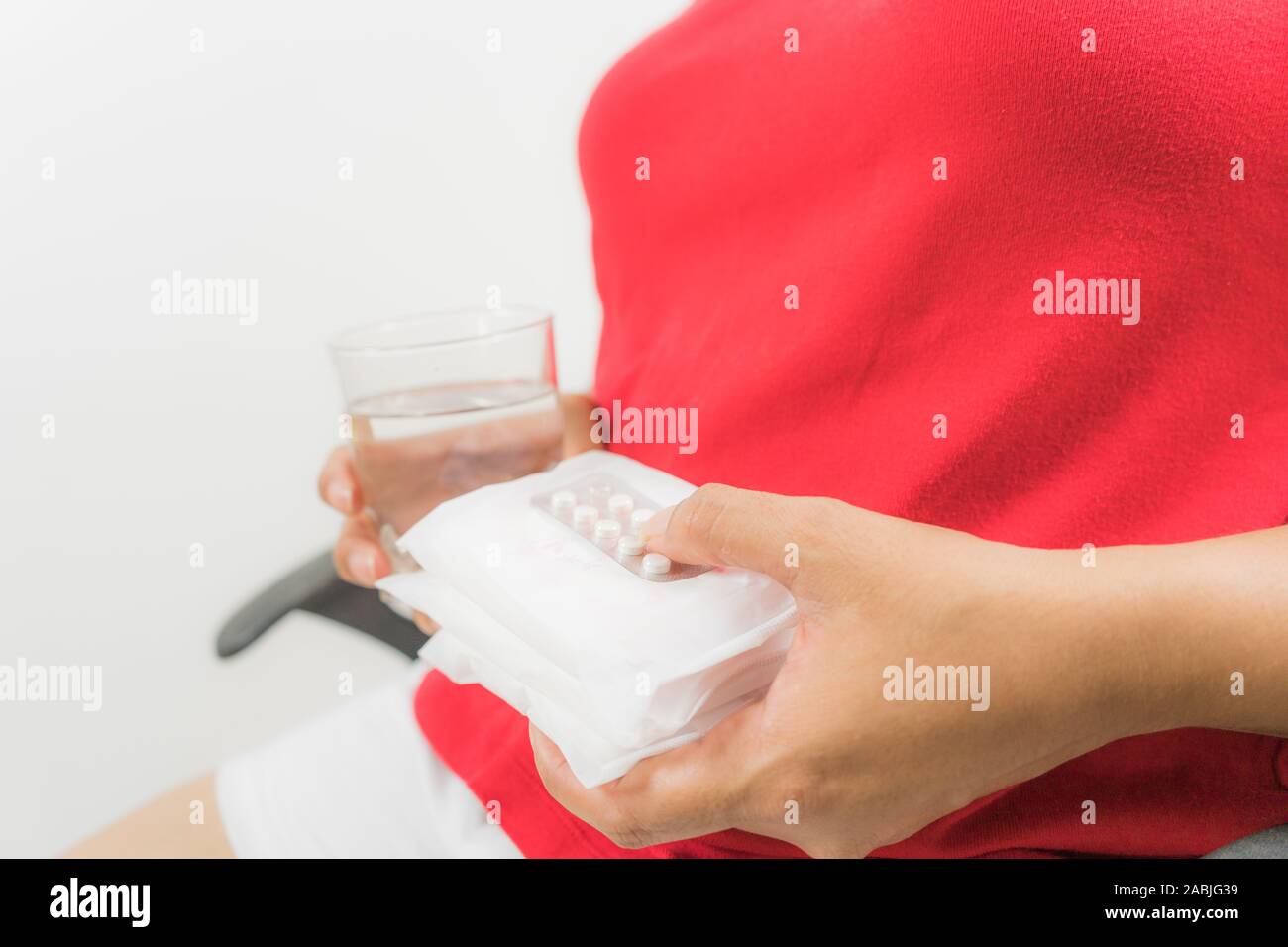 Inquiétude Jeune femme tenant comp verre d'eau à la maison et mal de périodes douloureuses Banque D'Images