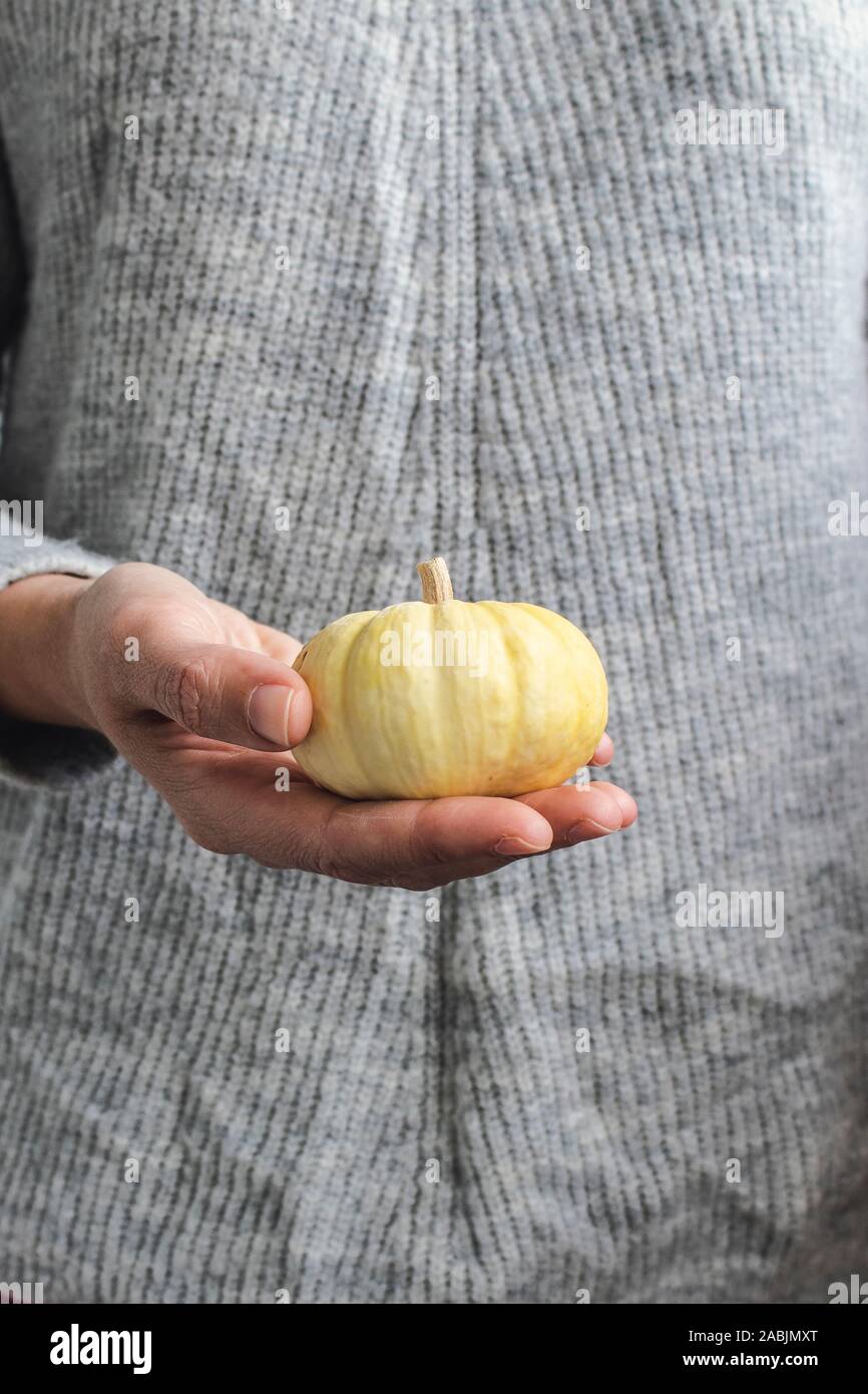 Jeune femme tenant une citrouille décoration miniature dans sa main Banque D'Images