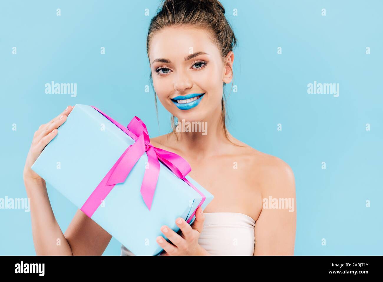 Heureux belle femme avec les lèvres bleues holding gift isolé sur blue Banque D'Images