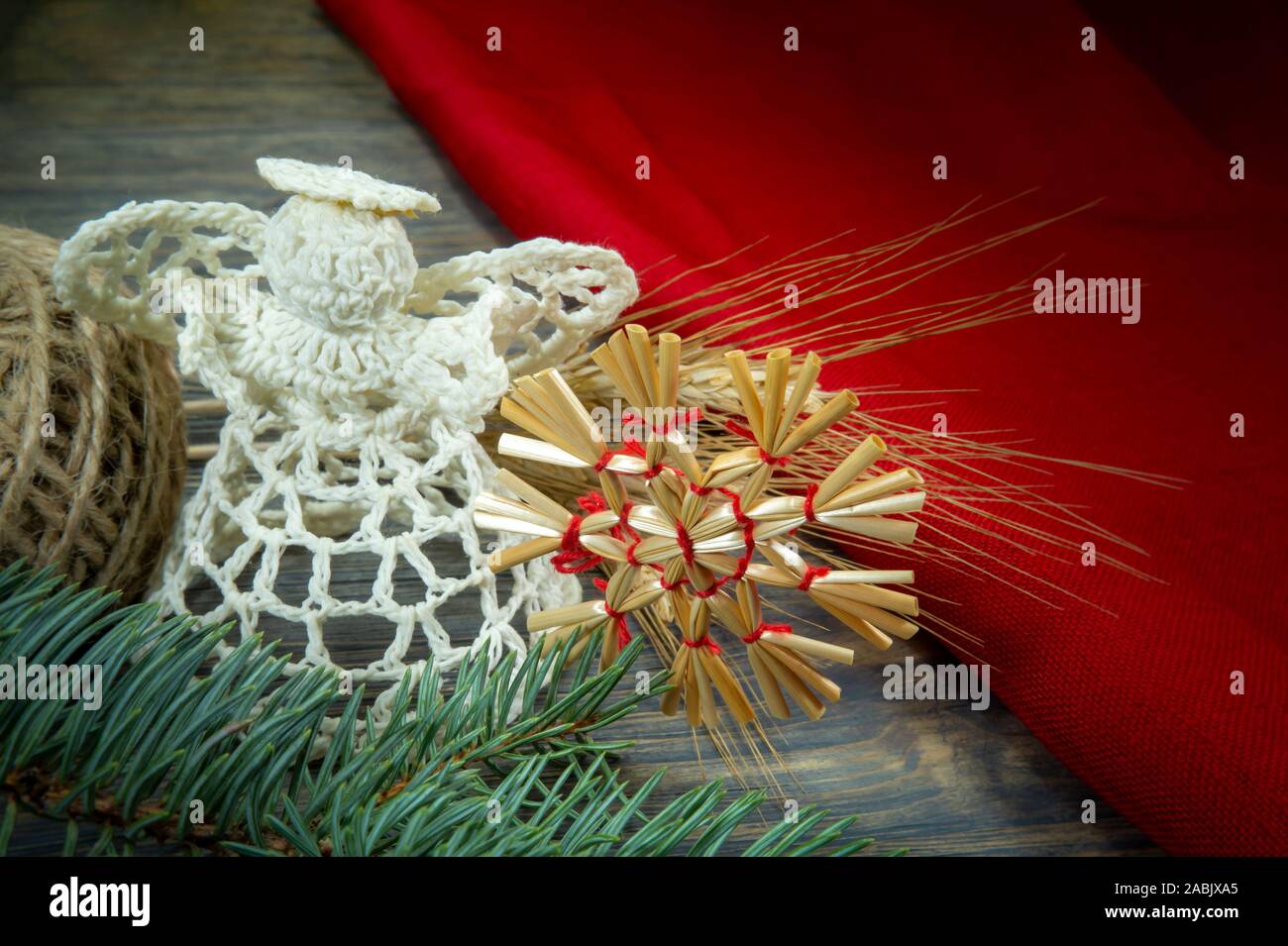 Fond de Noël avec des ornements faits à la main, y compris un ange de bonneterie thread et une paille star attaché avec de la ficelle rouge sur un bois rustique background Banque D'Images