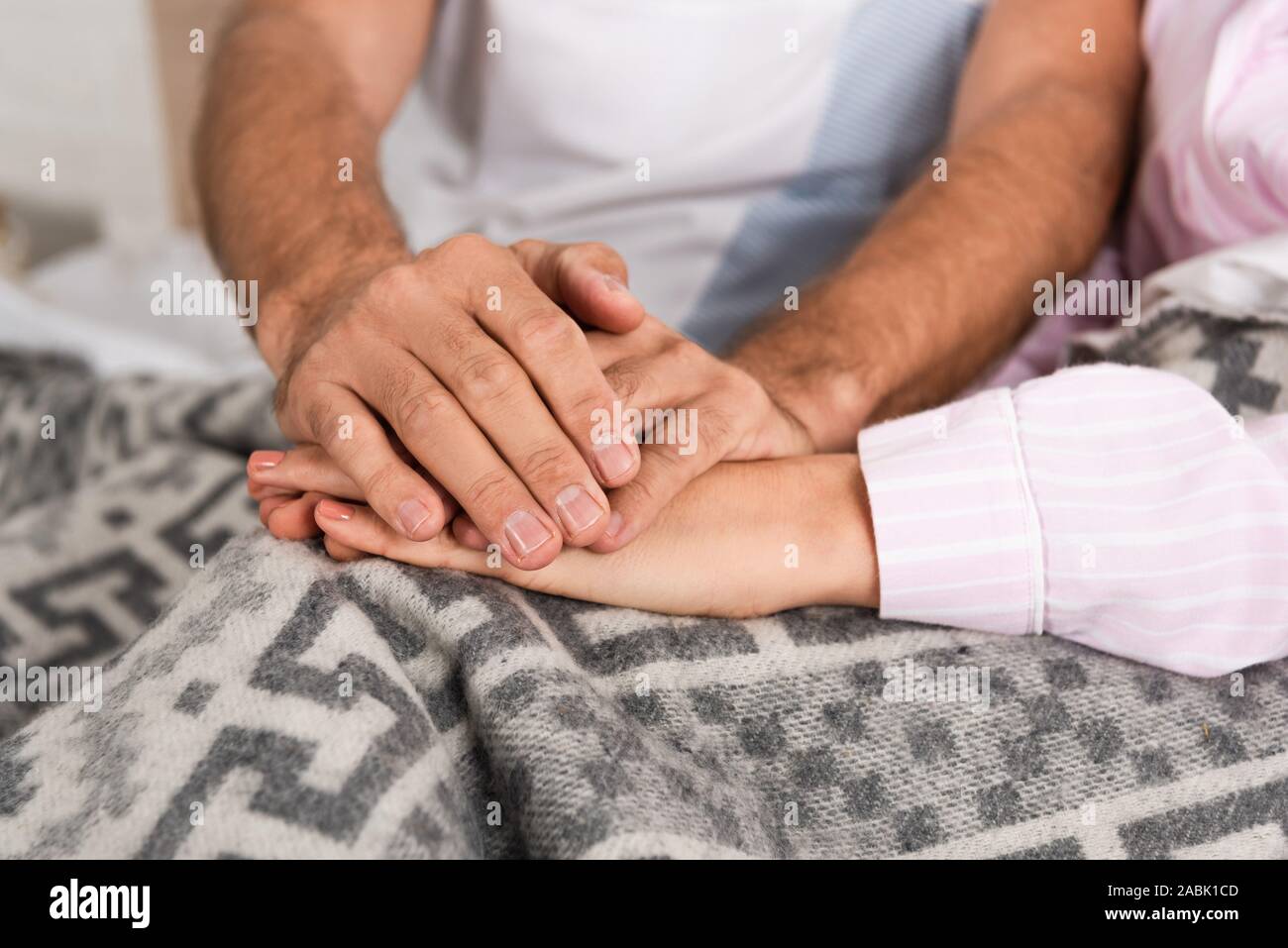 Portrait de couple holding hands on blanket in bed Banque D'Images