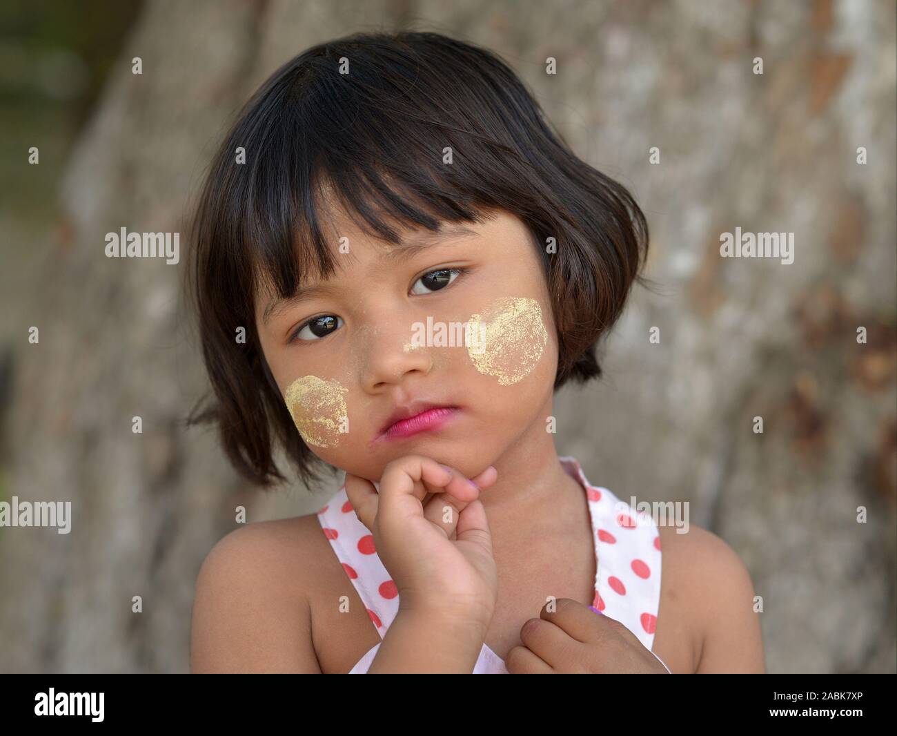 Jolie petite fille birmane avec correctifs de thanaka cosmétique traditionnelle face sur ses joues pose pour la caméra. Banque D'Images