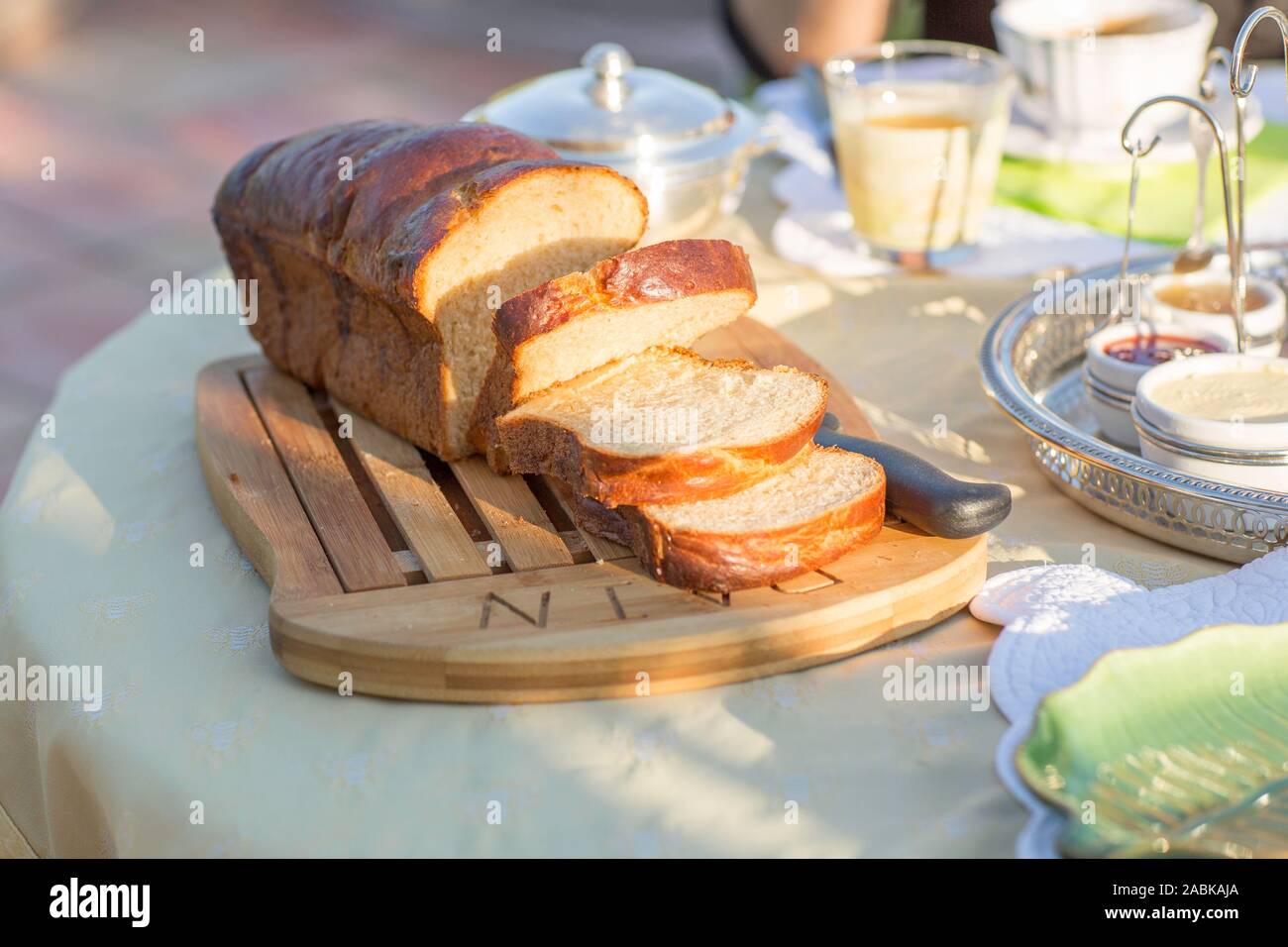 Petit-déjeuner fait maison brioche française sur une planche à découper, des confitures dans cups sur une journée ensoleillée en été le matin. Bon sentiment. Détail vert Banque D'Images