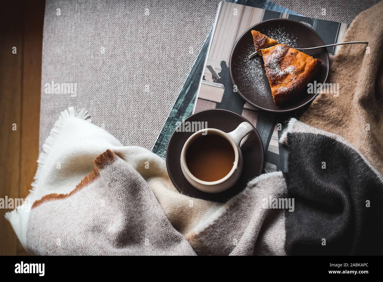 Week-end matin lente sur un canapé avec un café et un morceau de gâteau. L'humeur sombre flatlay Banque D'Images
