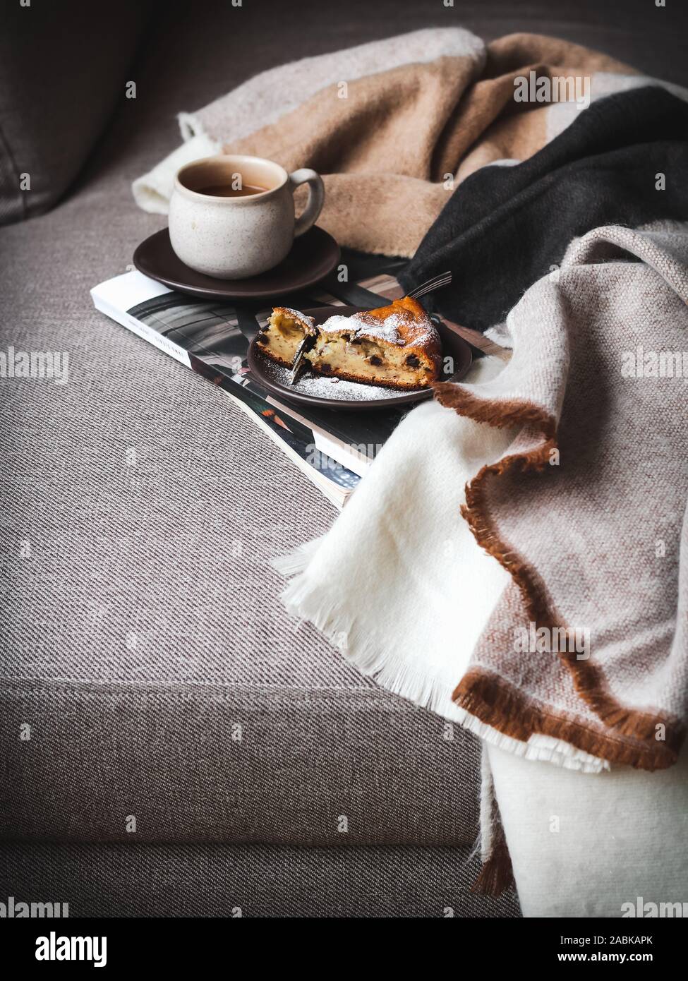 Week-end matin lente sur un canapé avec un café et un morceau de gâteau. Banque D'Images