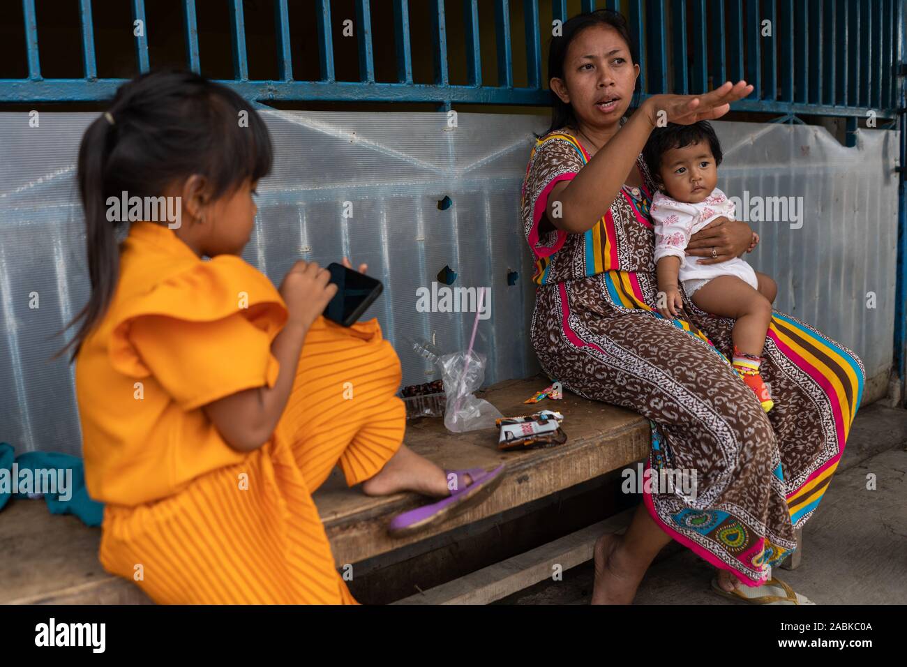 Jakarta, Indonésie. 18 Oct, 2019. Elle siège avec Irma ses filles devant sa maison à Muara Baru, une zone au-dessous du niveau de la mer qui est souvent affectée par les inondations. (Dpa-Stroy : 'la mer, le mur et la puissance de la destruction de la nature") Credit : Fauzan Ijazah/dpa/Alamy Live News Banque D'Images
