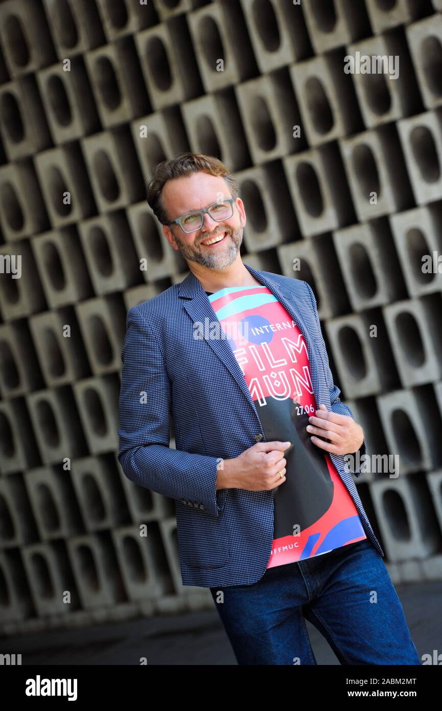 Christoph Gröner, directeur artistique du Festival du Film de Munich, enveloppé dans une affiche du 37e Festival du Film de Munich. [Traduction automatique] Banque D'Images