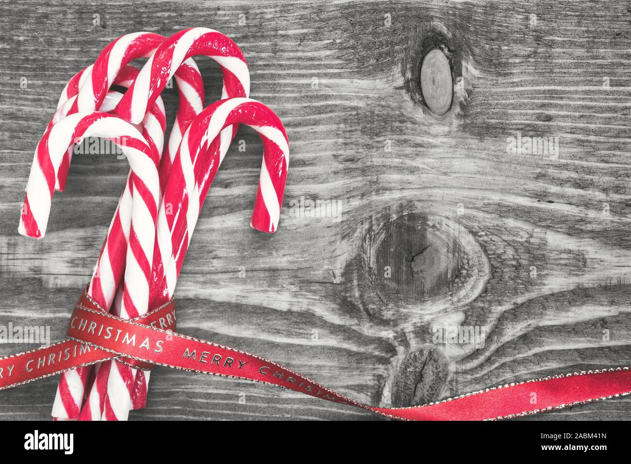 Des cannes de bonbon enveloppé de ruban de Noël rouge sur fond noir et blanc. Vue de dessus avec l'exemplaire de l'espace sur le côté droit. Banque D'Images