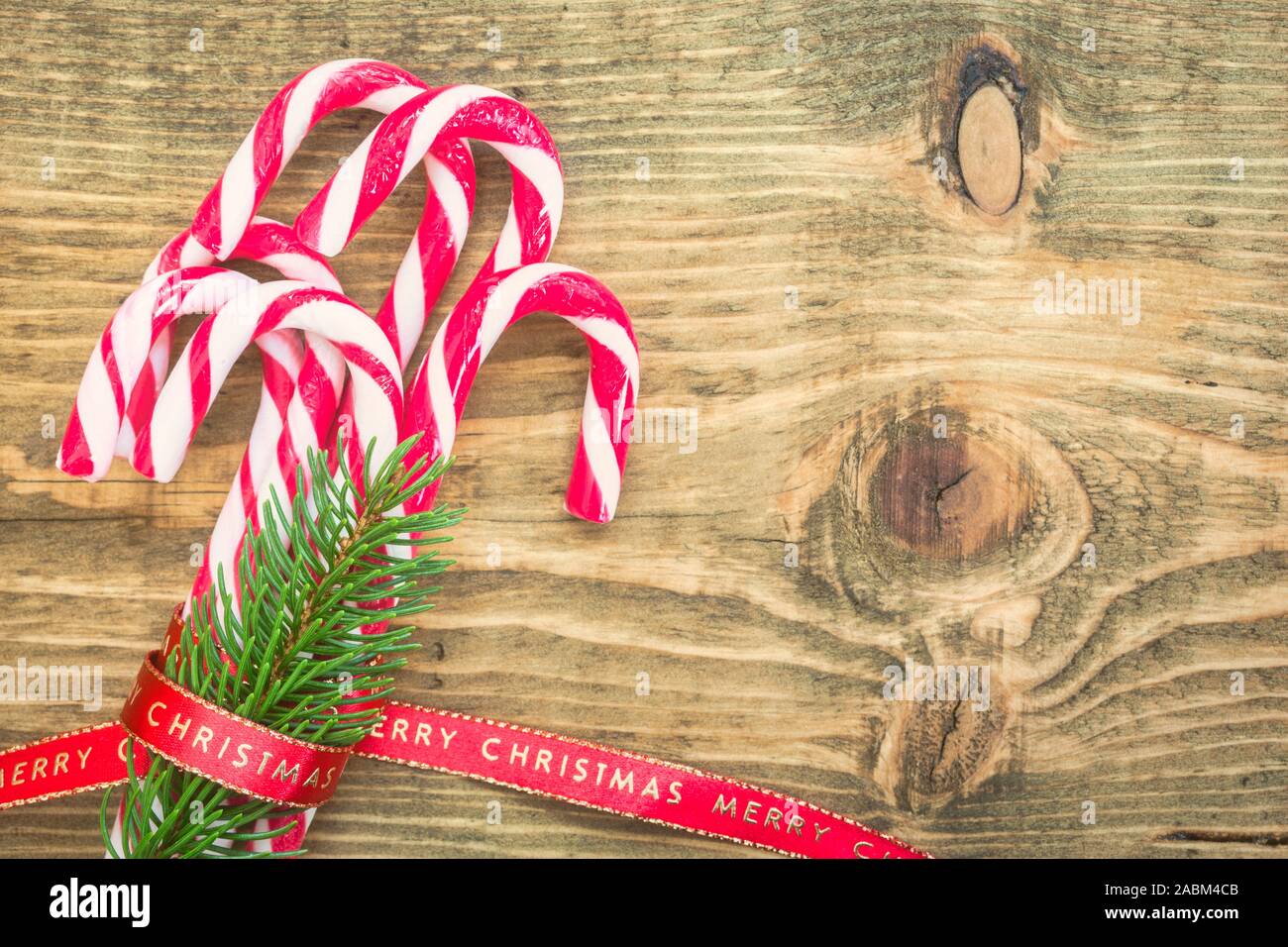 Des cannes de bonbon enveloppé de ruban rouge de Noël sur fond de bois. Tons vintage photo. Vue de dessus avec l'exemplaire de l'espace sur le côté droit. Banque D'Images