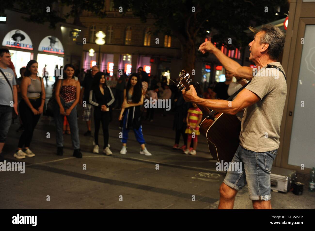 Un musicien de rue joue sur une chaude nuit d'été dans la zone piétonne de Kaufingerstraße. [Traduction automatique] Banque D'Images