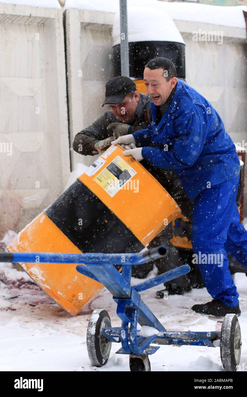 Les travailleurs de garage salopette bleue sont chargement sur une brouette  d'un baril de carburant, le baril, pour le ravitaillement des véhicules  Photo Stock - Alamy