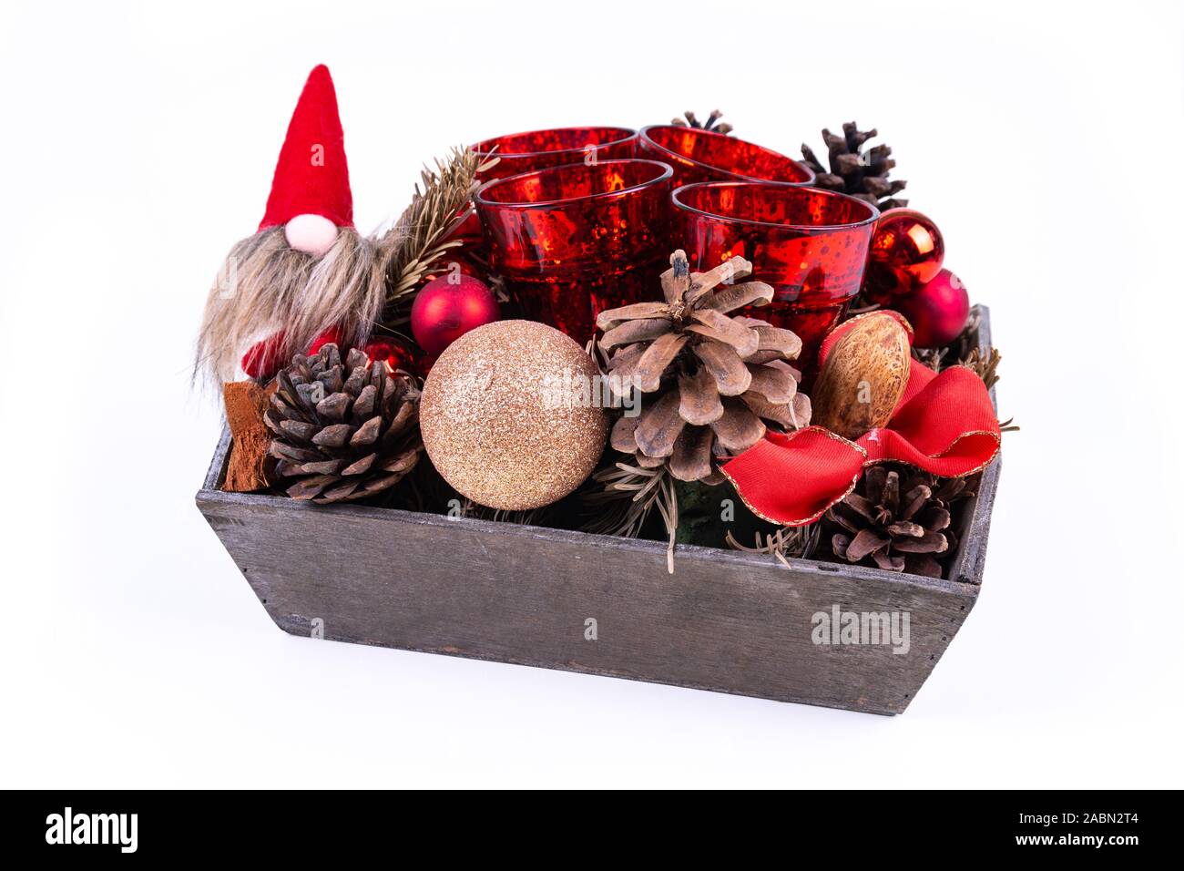 Une couronne de Noël avec des pommes de pins, des boules de Noël, des bougies et un nain sur fond blanc - vue oblique Banque D'Images