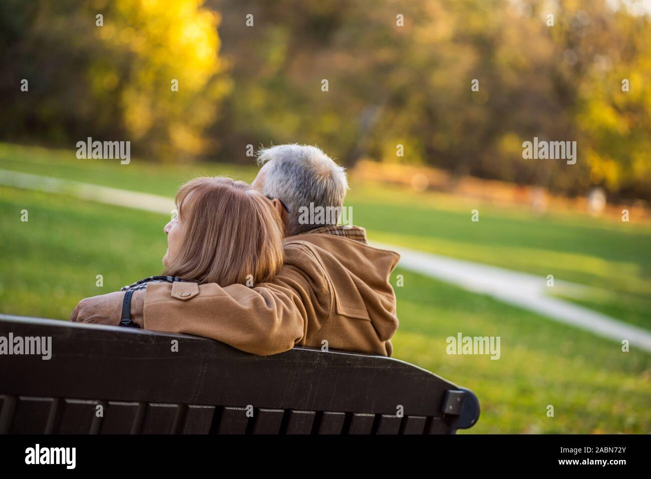 Romantic senior couple est assis sur un banc dans le parc et profiter de l'automne. Banque D'Images