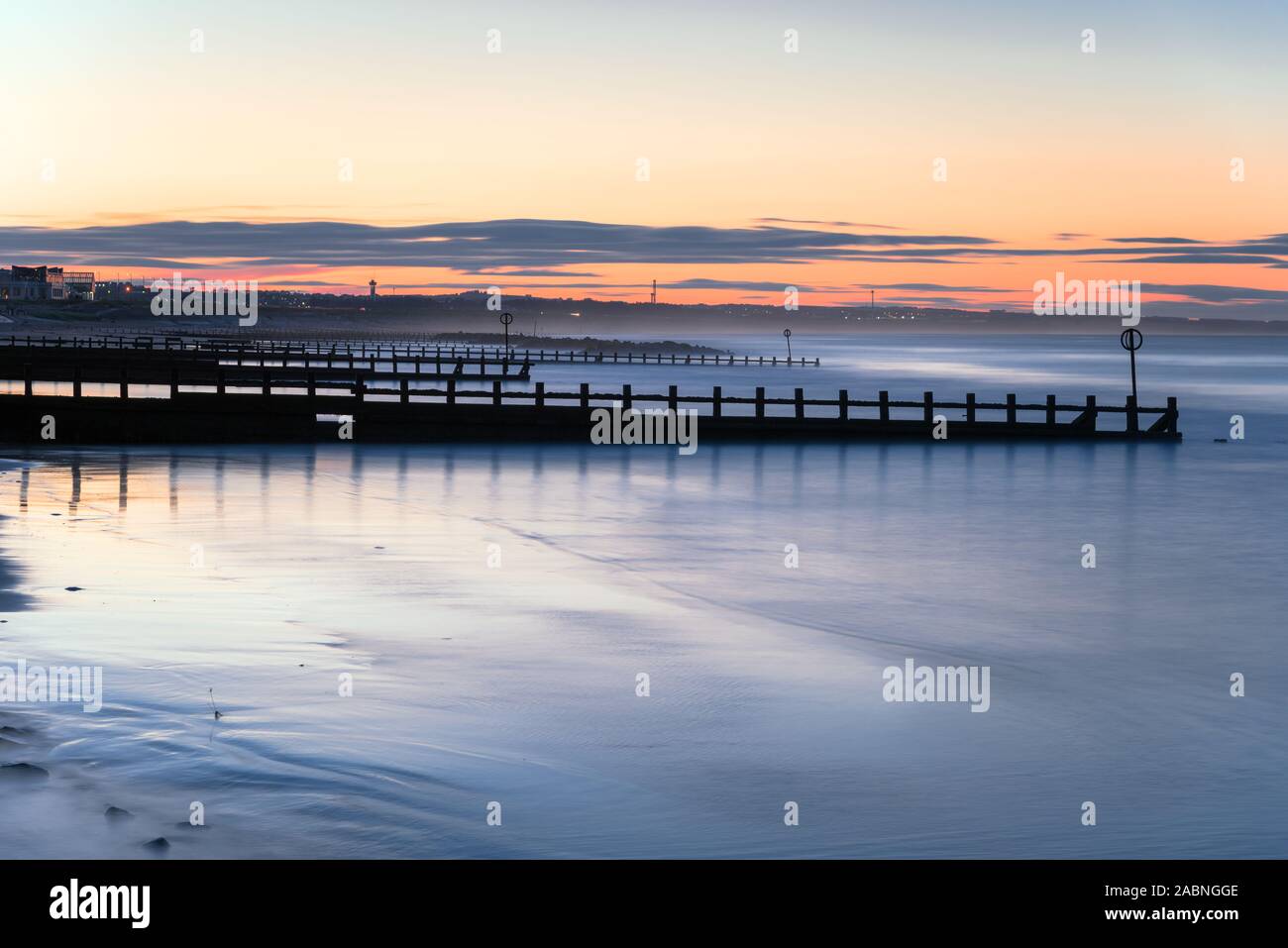 Vue d'une plage de sable avec des épis au crépuscule Banque D'Images