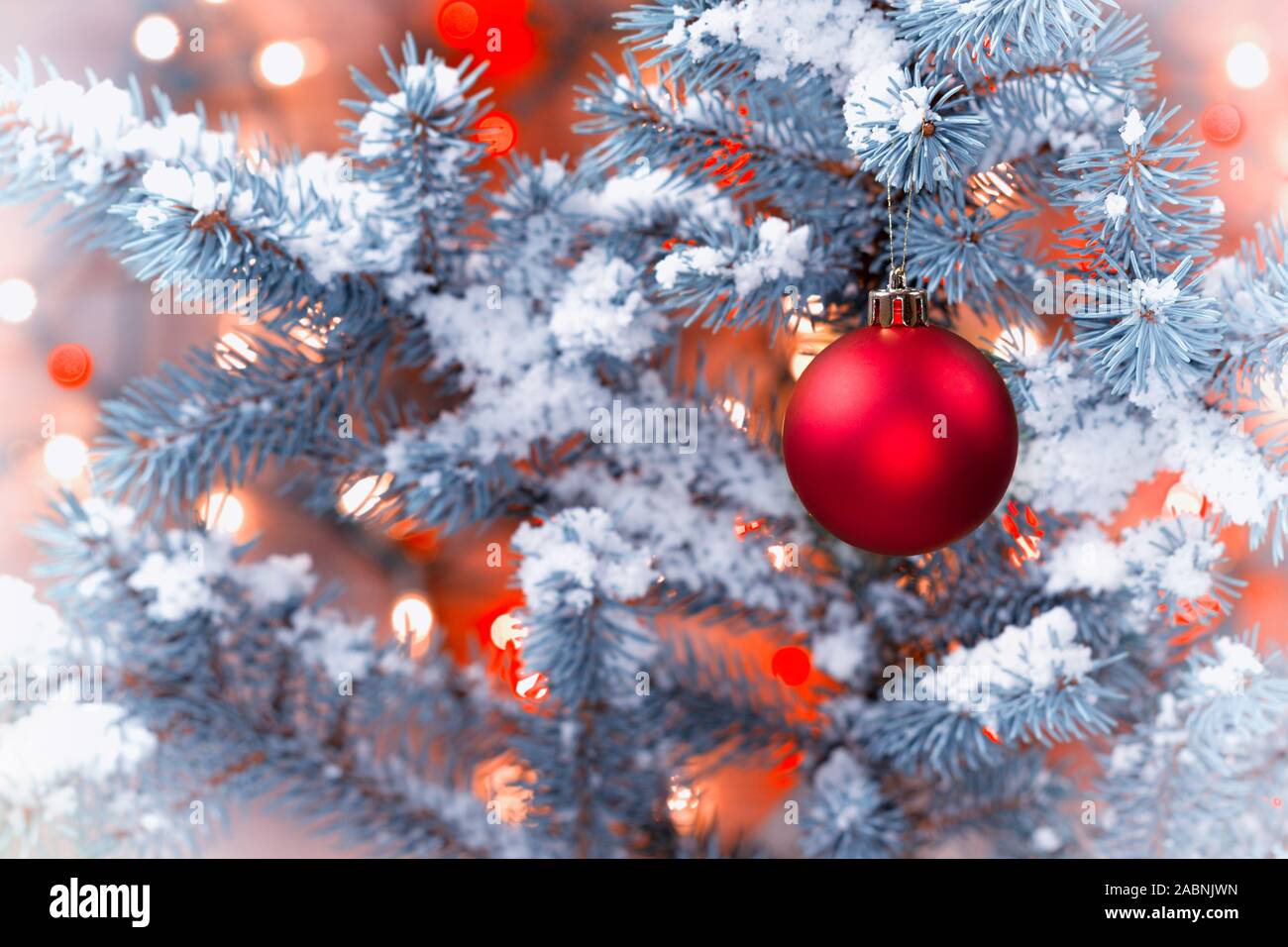 Libre de droit horizontal d'un seul red Christmas ornament hanging from tree pin couvert de neige avec feux lumineux en format vintage Banque D'Images