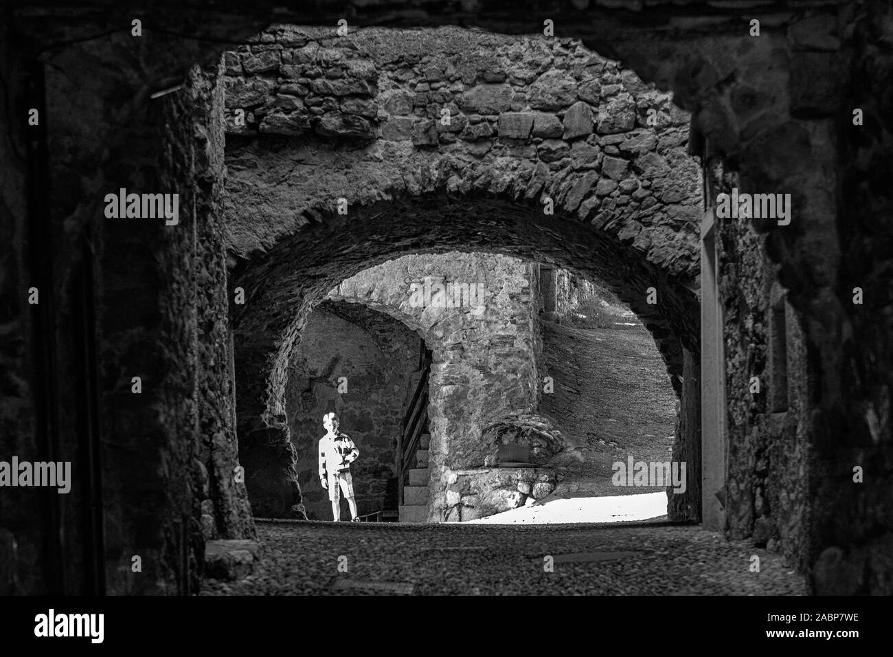 Via Fratelli Bandiera, un tunnel étroit, à travers les arches, Canale di Tenno, Trentino-Alto Adige, Italie. Version noir et blanc Banque D'Images