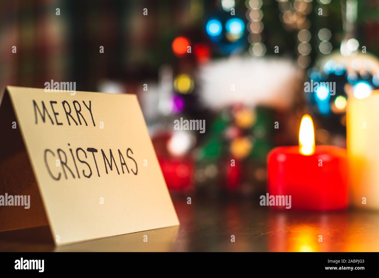 Joyeux Noël écrit sur une carte de vœux sous un arbre de Noël avec des décorations et ornements. Célébration festive. Banque D'Images