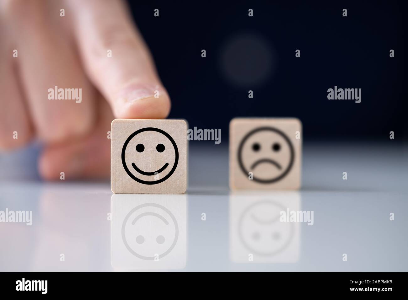 Close-up of Person's Hand Holding Bloc En bois avec heureux et malheureux face réfléchissante sur 24 Banque D'Images