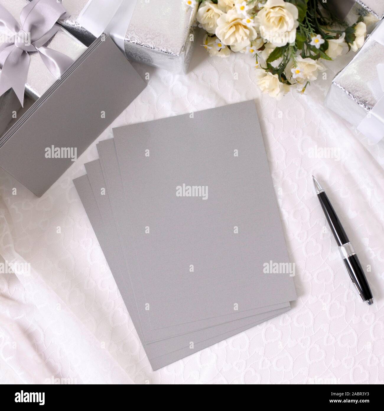 Argent gris papier d'écriture ou des invitations avec enveloppes posées sur bustier dentelle avec plusieurs cadeaux de mariage et de bouquets de roses blanches. L'espace pour copier. Banque D'Images Argent gris papier d'écriture ou des invitations avec enveloppes posées sur bustier dentelle avec plusieurs cadeaux de mariage et de bouquets de roses blanches. L'espace pour copier. Banque D'Images