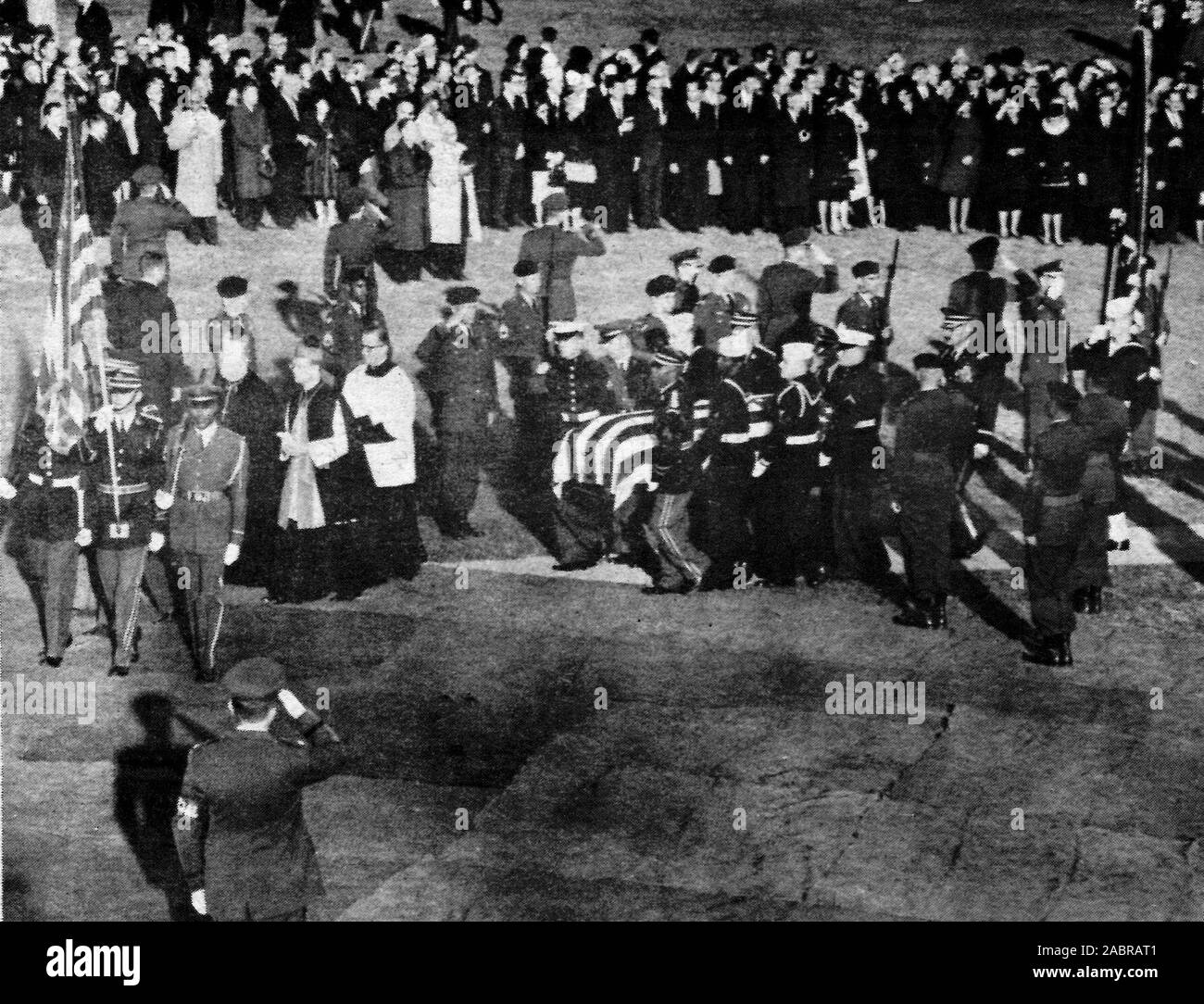 Un garde militaire et de trois membres du clergé catholique romain précéder le cercueil de feu John F. Kennedy, 35e président des États-Unis, car il est supporté par un joint services garde d'honneur à son dernier lieu de repos dans le Cimetière National d'Arlington. Banque D'Images