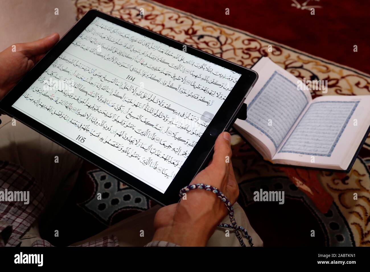 Une lecture musulmane Coran numérique sur une tablette.en arrière-plan un document papier traditionnel arabe Saint Coran. Banque D'Images
