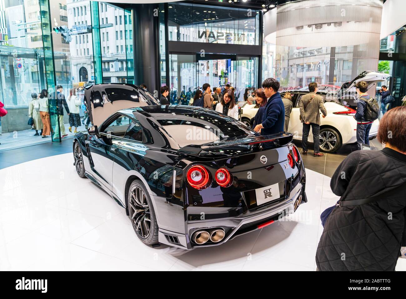 Phare Nissan showroom, Ginza, Tokyo. Personnes regardant l'écran d'un noir de haute performance voiture de sport, la RTM dans la principale salle d'exposition. Banque D'Images
