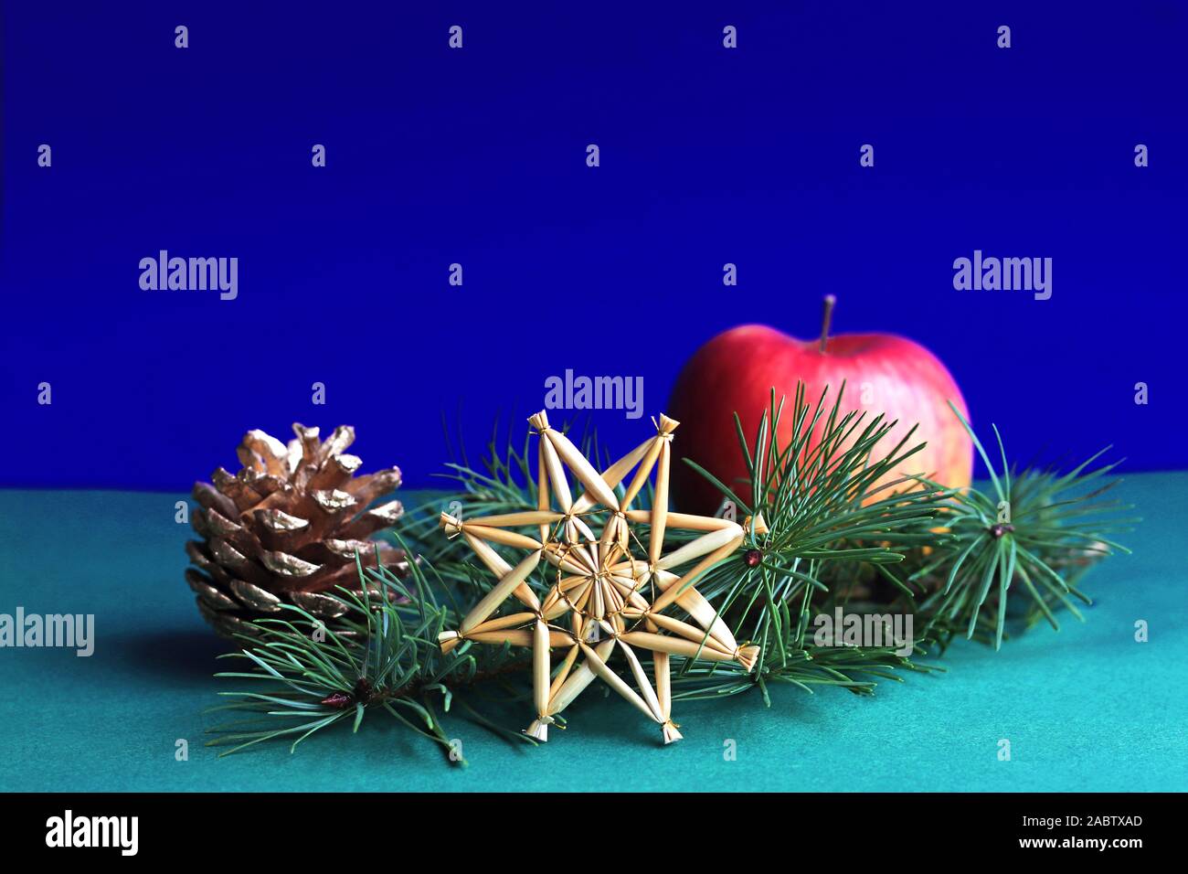 Carte de Noël rétro avec une paille star, de conifères et apple en face d'un fond bleu foncé Banque D'Images