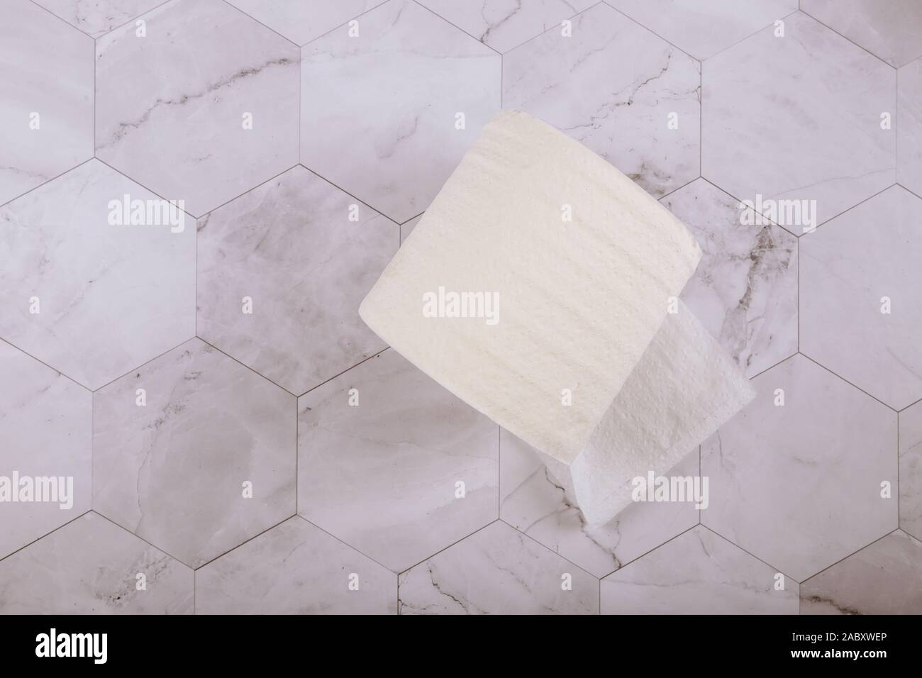 Rouleau de papier toilette doux sur du carrelage blanc dans la salle de bains Banque D'Images