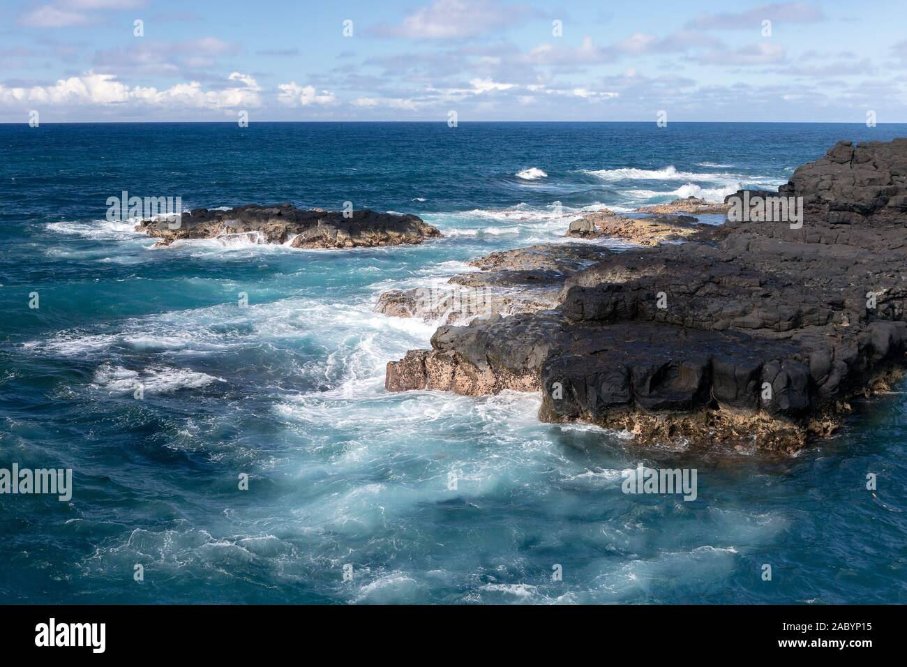 Autour de l'eau océan ondulé Swirly roche volcanique près de Queen's Bath à Princeville, île de Kauai, Hawaii. L'océan sans fin, ligne d'horizon, quelques nuages. Banque D'Images