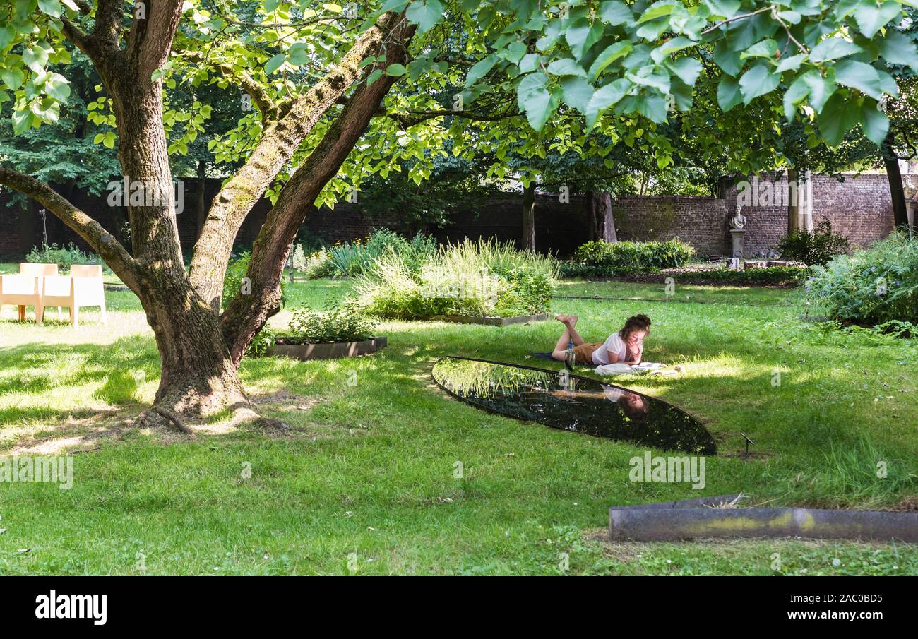 Anderlecht, Bruxelles / Belgique - 0626 2019 : des vêtements d'été en lecture à la pelouse verte, couché sur son ventre Banque D'Images