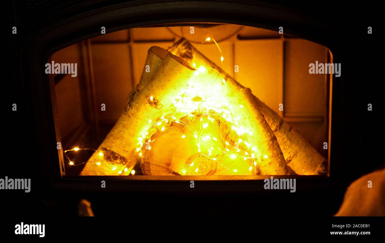 Pile de bois de chauffage et de la guirlande sur fond clair, vue en gros - le temps de Noël Banque D'Images