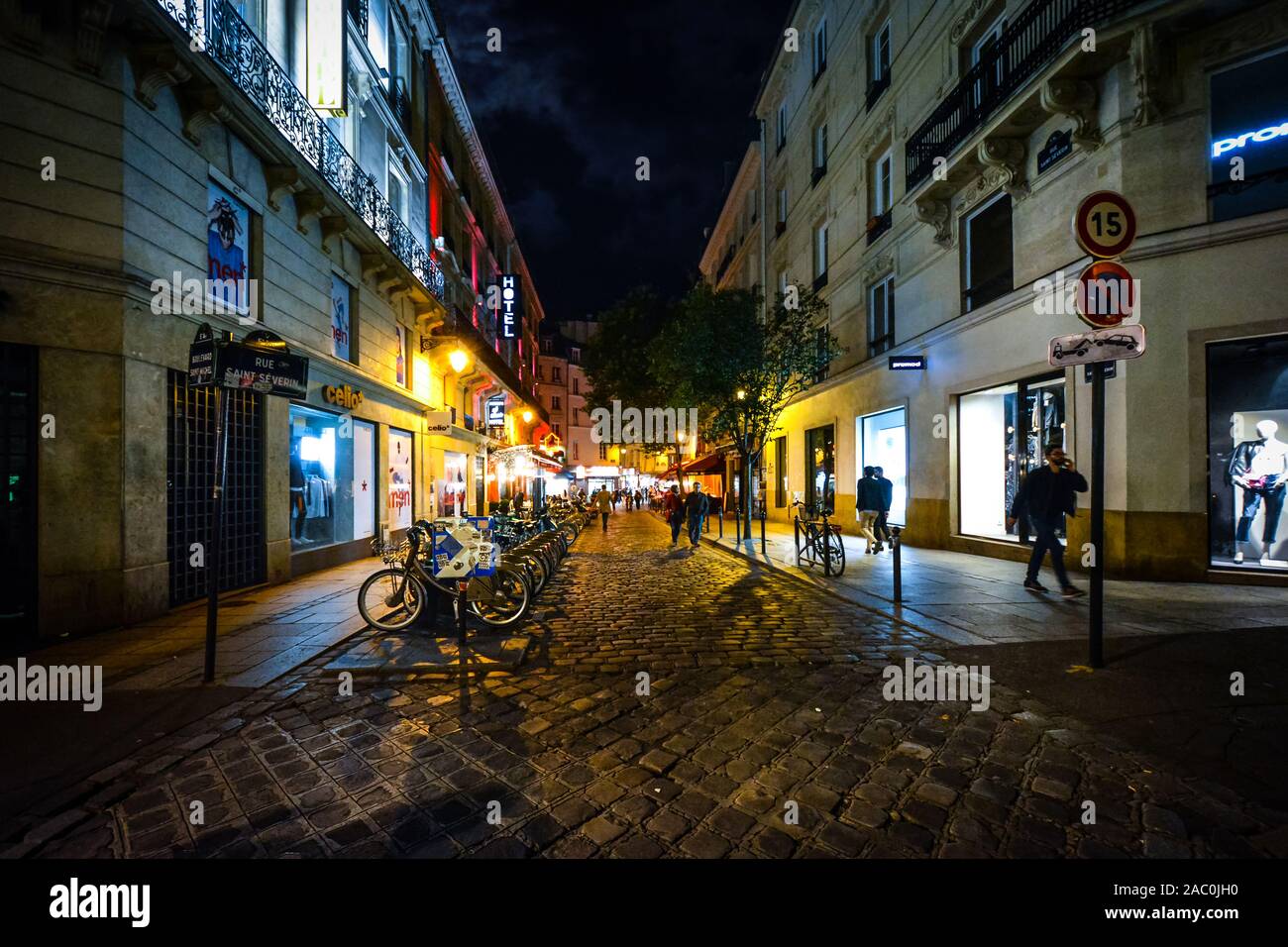 Les touristes profiter d'une fin de nuit à pied sur une rue animée colorée, illuminée par un café et boutique des lumières dans le quartier Latin de Paris, France. Banque D'Images