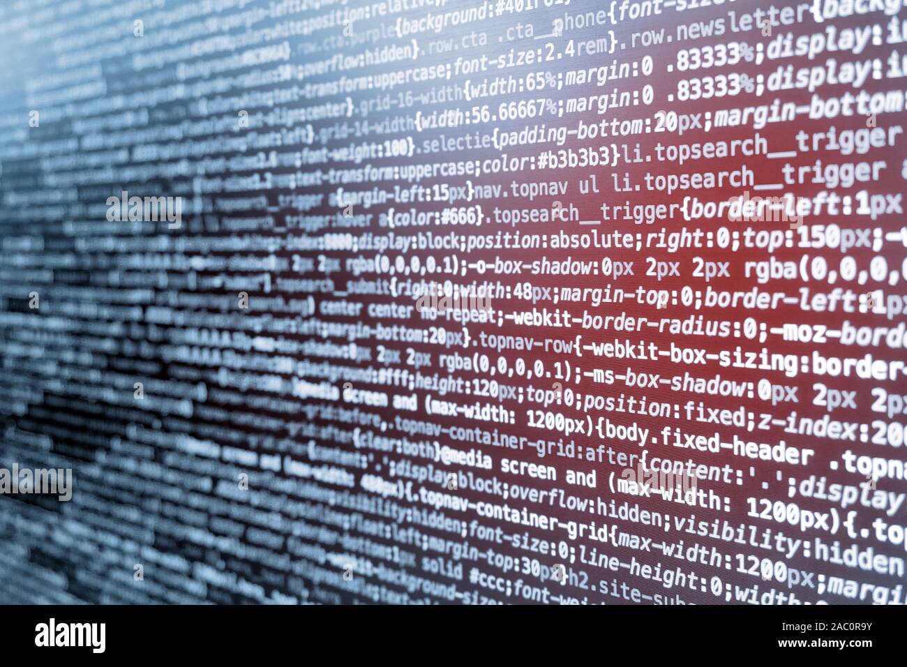 Le code de programmation CSS compressé à l'écran dans des tons bleus et fuite de lumière rouge Banque D'Images