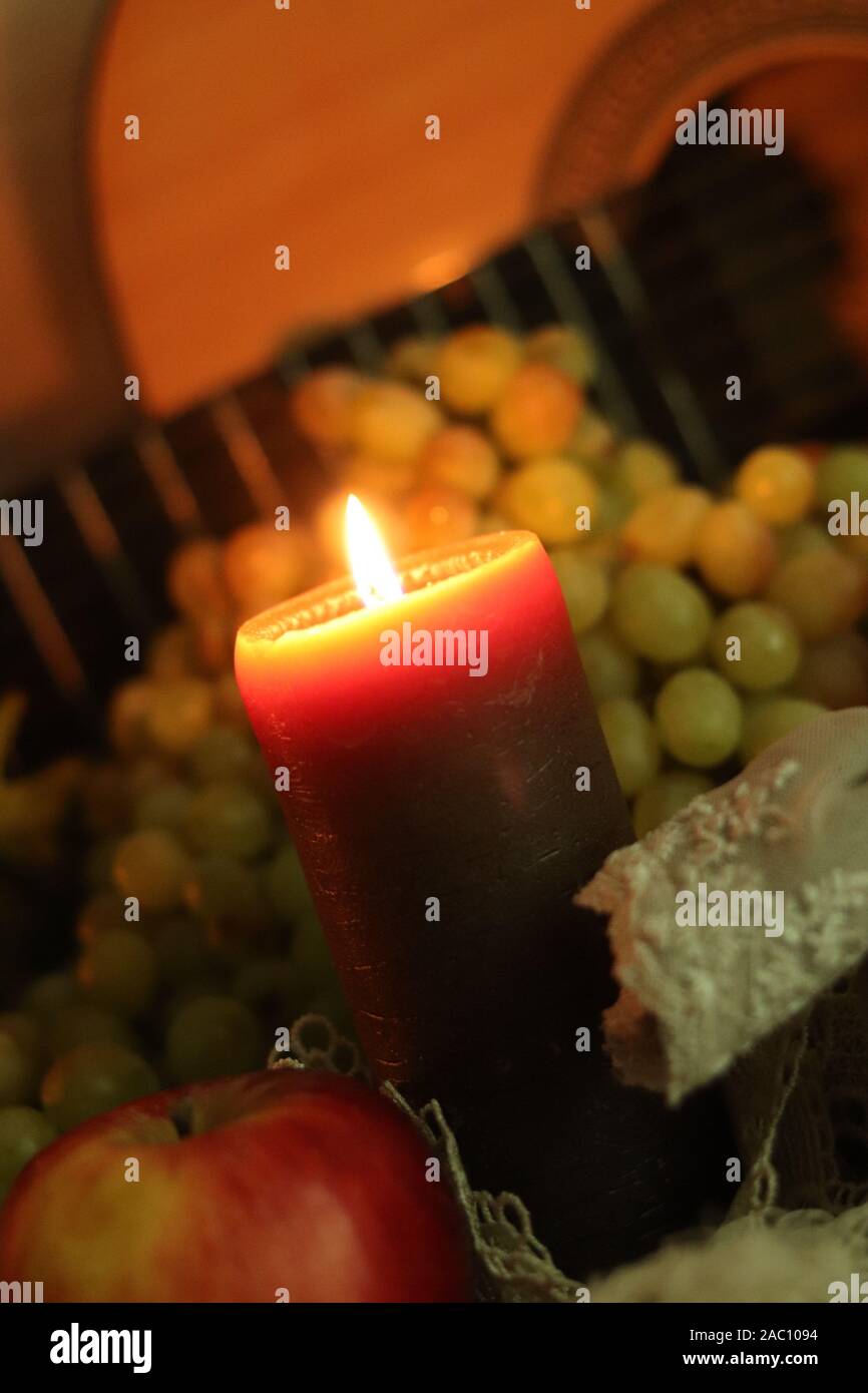 La chaleur de la maison d'automne encore la vie. Bougie brune lumière douce sur table avec raisins verts frais et pomme rouge avec guitare Banque D'Images