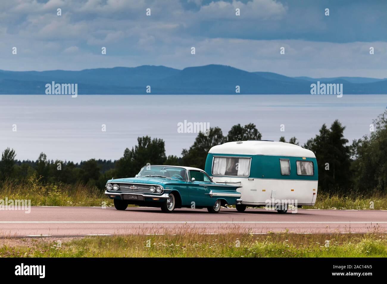American Classic car, Chevrolet Impala Coupé construit 1960, avec caravane rétro, le lac Siljan à l'arrière, près de Rattvik, dalarna, Suède Banque D'Images