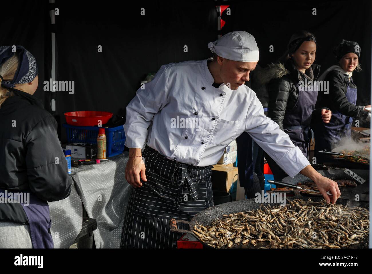 Le corégone blanc frit sur grande poêle à hareng baltique juste en place du marché d'Helsinki, Finlande. Jeune chef contrôle de la qualité. Banque D'Images