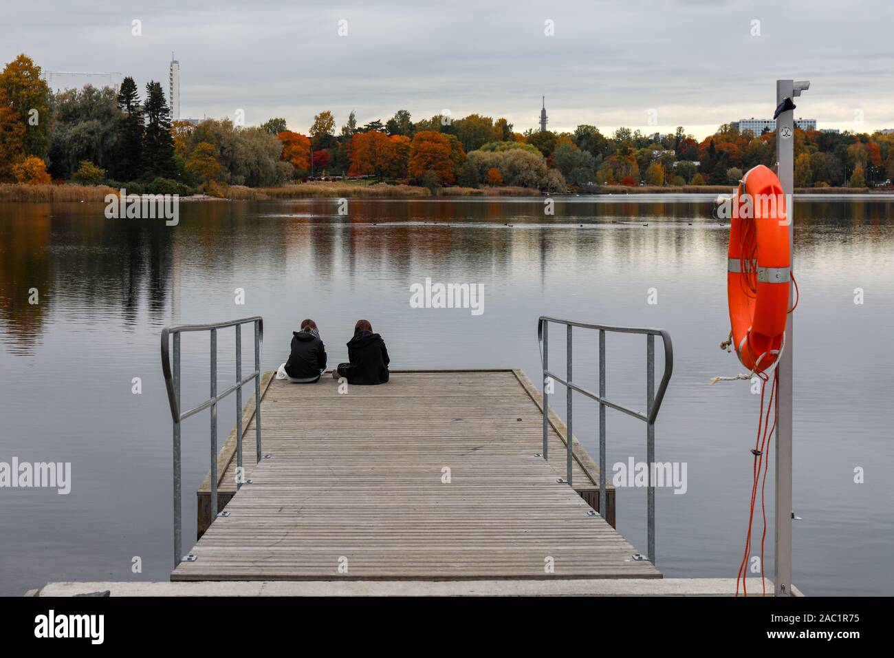 Amis assis sur un quai à la baie de Töölönlahti dim sur un jour d'automne à Helsinki, Finlande Banque D'Images