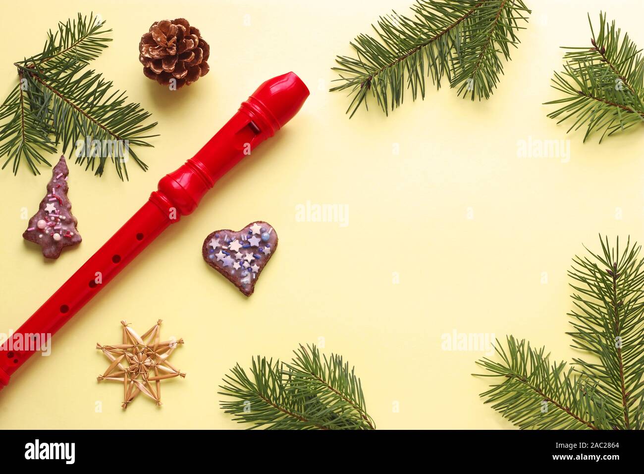 Carte de vœux de Noël avec un recoreder rouge, des branches de pins et cône de pin, paille star et biscuits de Noël sur un fond jaune avec copie espace Banque D'Images